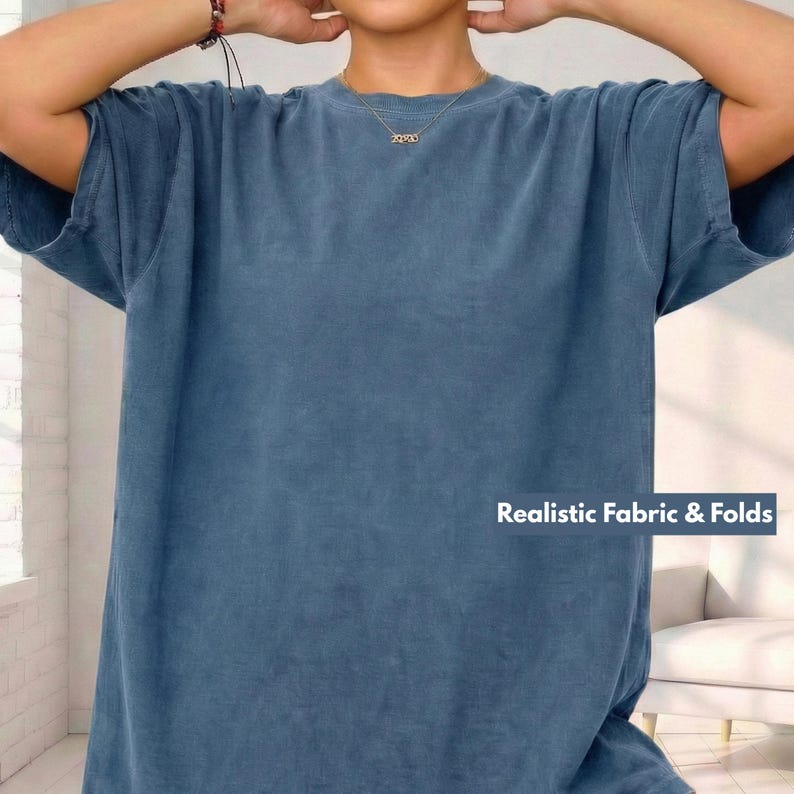May include: A blue short-sleeved t-shirt with the text "Realistic Fabric & Folds" in white. The shirt has a relaxed fit and a slightly faded appearance. The fabric appears soft and comfortable.