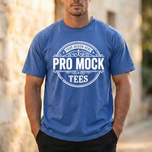 May include: A blue t-shirt with the text "YOUR DESIGN HERE PRO MOCK TEES" in a white circular design. The shirt is short-sleeved and has a crew neck.