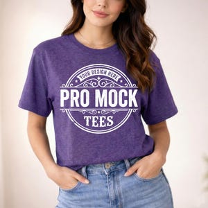 May include: A purple t-shirt with the text "PRO MOCK TEES" in a white circular design. The shirt is short-sleeved and made of a textured fabric. The model is wearing blue jeans.
