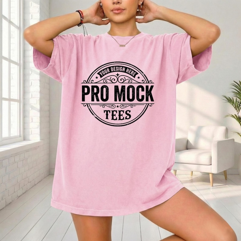 May include: A light pink t-shirt with a large black circular graphic that reads "YOUR DESIGN HERE" at the top, and "PRO MOCK TEES" in the center. The shirt has short sleeves and a relaxed fit.