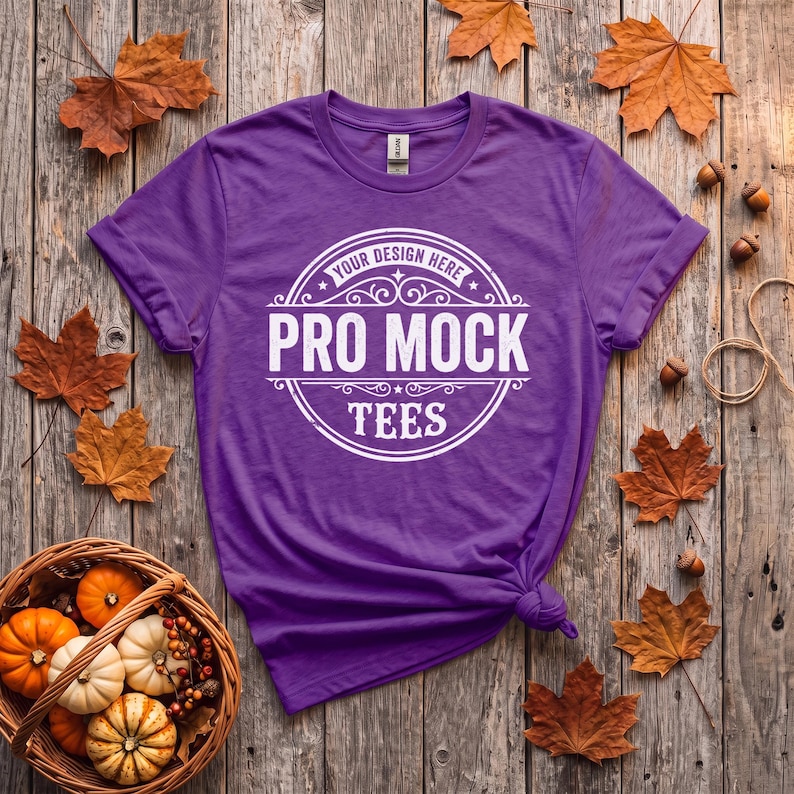 May include: A purple short-sleeve t-shirt featuring a white circular graphic print with the text "YOUR DESIGN HERE", "PRO MOCK", and "TEES" centered on the chest. The shirt has a crew neckline and a tag visible at the inner collar.
