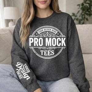 May include: Dark gray sweatshirt with the text "PRO MOCK TEES" in a white circular design on the front. The sleeve features the text "YOUR DESIGN HERE" in white. The sweatshirt is a mock-up for design placement.