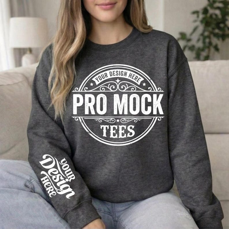May include: Dark gray sweatshirt with the text "PRO MOCK TEES" in a white circular design on the front. The sleeve features the text "YOUR DESIGN HERE" in white. The sweatshirt is a mock-up for design placement.