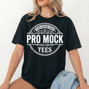 Peut inclure: T-shirt noir avec un motif circulaire blanc portant l'inscription "YOUR DESIGN HERE", "PRO MOCK" et "TEES". Le t-shirt &agrave; manches courtes a un col rond et est fait d'une mati&egrave;re douce.