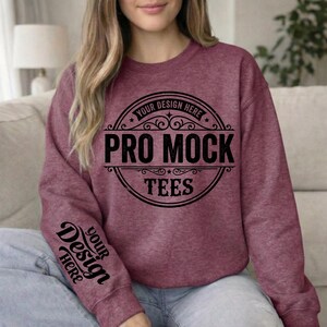 May include: Burgundy crewneck sweatshirt with the text "PRO MOCK TEES" in a circular design on the front. The sleeve features the text "YOUR DESIGN HERE". The sweatshirt is a solid color and appears to be made of a soft material.
