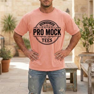May include: A peach-colored t-shirt with the text "PRO MOCK TEES" in a black circular design. The shirt is short-sleeved and appears to be made of a soft material. The text "YOUR DESIGN HERE" is above the main text.