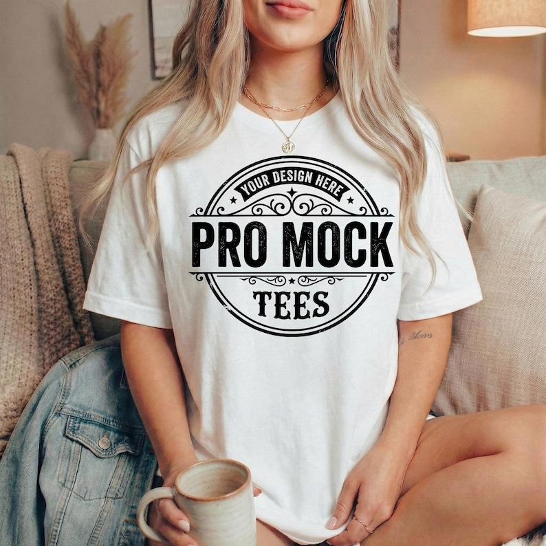 Peut inclure: T-shirt blanc avec un motif circulaire noir. Le texte "Your Design Here" est en haut et "Pro Mock Tees" au centre. Le mod&egrave;le porte un mug. Le t-shirt est de style d&eacute;contract&eacute;.