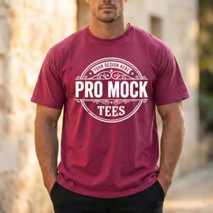 May include: A maroon t-shirt with a white circular graphic that reads "YOUR DESIGN HERE" at the top, and "PRO MOCK TEES" in the center. The shirt is short-sleeved and has a crew neck.