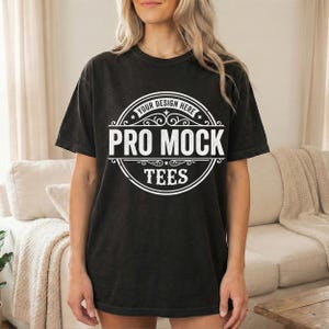 May include: Black t-shirt with a white circular design that reads "Your Design Here" at the top, "Pro Mock" in the center, and "Tees" at the bottom. The shirt is worn by a person.