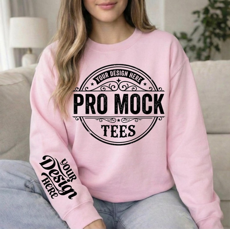 May include: A light pink sweatshirt with the text "PRO MOCK TEES" in a black circular design on the front. The sleeve has the text "YOUR DESIGN HERE" in black. The sweatshirt is a crew neck style.