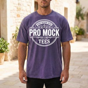 May include: A purple t-shirt with the text "PRO MOCK TEES" in a white circular design. The shirt has short sleeves and a crew neck. The text "YOUR DESIGN HERE" is above the main text.