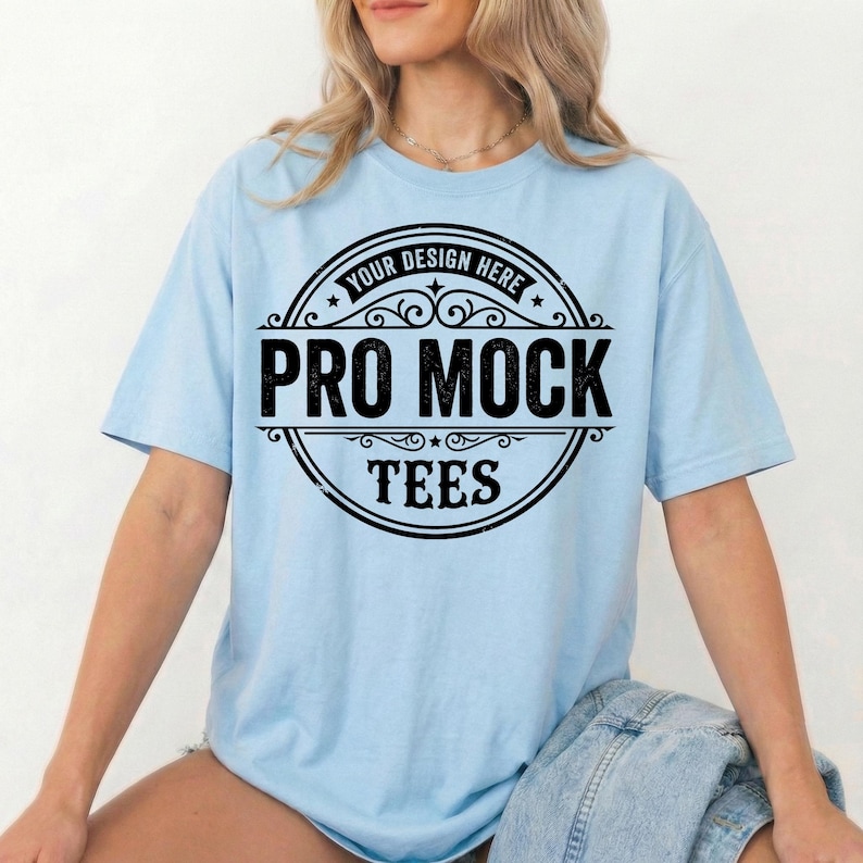 Peut inclure: T-shirt bleu clair avec un motif noir circulaire. Le motif comprend les mots "YOUR DESIGN HERE", "PRO MOCK" et "TEES". Le t-shirt &agrave; manches courtes a une coupe ample.