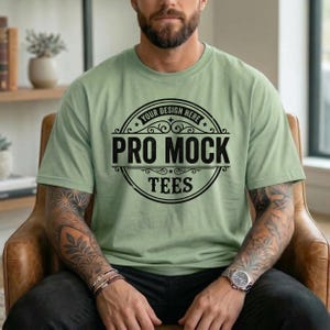 May include: A light green t-shirt with the text "PRO MOCK TEES" in a black, circular design. The shirt is short-sleeved and appears to be made of a soft material. The words "YOUR DESIGN HERE" are arched above the main text.
