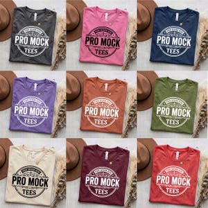 Puede incluir: Nueve camisetas de diferentes colores, incluyendo gris, rosa, azul marino, morado, naranja, verde oliva, beige, burdeos y rojo. Cada camiseta presenta el texto "PRO MOCK TEES" en un diseño circular.
