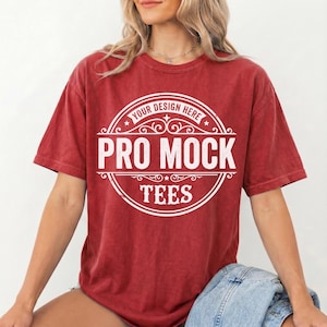 May include: A red t-shirt with a white circular design that reads "Your Design Here" at the top, "Pro Mock" in the center, and "Tees" at the bottom. The shirt is a solid red color and has short sleeves.