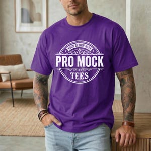 May include: A purple t-shirt with the text "PRO MOCK TEES" in a white circular design. The shirt has short sleeves and a crew neck. The text "YOUR DESIGN HERE" is above the main text.