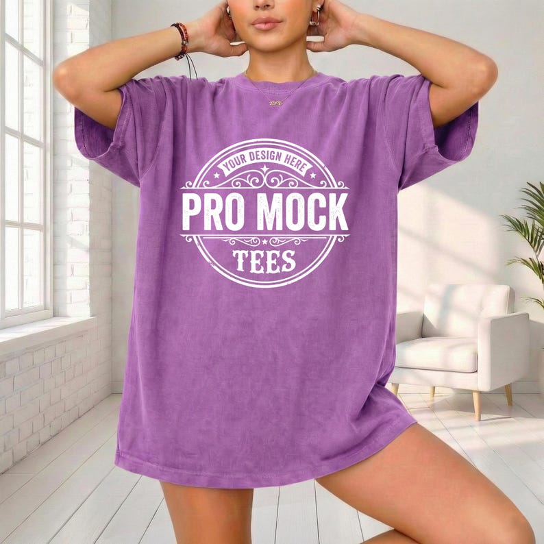 May include: A purple t-shirt with the text "PRO MOCK TEES" in a white circular design. The shirt is a solid color and has short sleeves. The model is wearing the shirt.