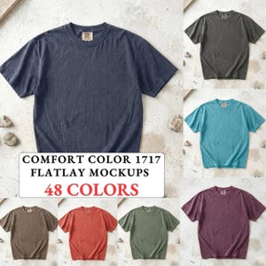 May include: A collection of short-sleeved crew neck t-shirts in various solid colors including navy, charcoal, teal, brown, orange, olive, and plum. A central white rectangular label displays the text COMFORT COLOR 1717 FLATLAY MOCKUPS 48 COLORS.