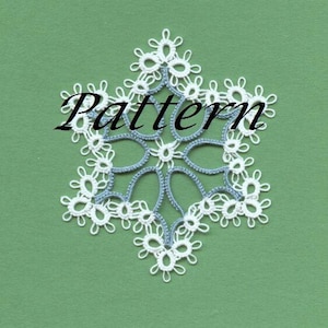 May include: A white and blue snowflake doily with the word "Pattern" in black text. The doily is made of delicate lace and is set against a green background. The snowflake design is intricate and detailed.