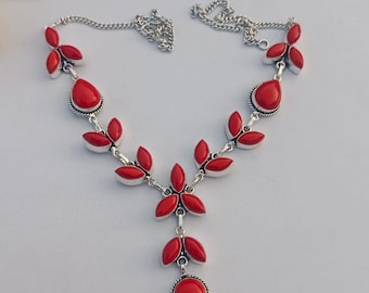 May include: A silver-toned necklace featuring vibrant red gemstone accents. The necklace has a chain and a central pendant with a teardrop-shaped stone. The design incorporates leaf-like and floral elements, creating an elegant and eye-catching piece.