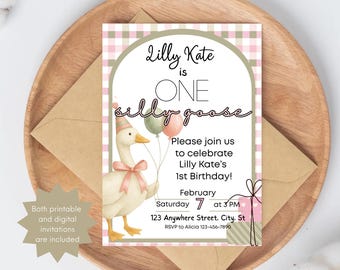Può includere: Invito di compleanno con un'illustrazione di un'oca e il testo "Lilly Kate compie UN anno". L'invito include i dettagli dell'evento ed è posto su un vassoio di legno con una busta di carta kraft. Invito per un primo compleanno.