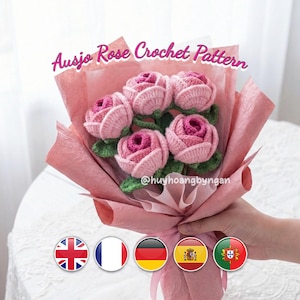 Peut inclure: Un bouquet de roses roses crochetées, enveloppé dans du papier rose. Le texte "Ausjo Rose Crochet Pattern" est visible. Le bouquet est tenu par une personne.