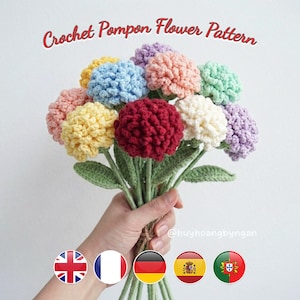 以下が含まれることがあります： 赤、黄、青、ピンク、緑、紫の色とりどりのかぎ針編みのポンポンフラワーのブーケ。花は緑の茎と葉でまとめられています。「Crochet Pompon Flower Pattern」というテキストが赤い筆記体で書かれています。