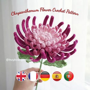 May include: A crocheted chrysanthemum flower in pink and magenta, with green leaves and stem. The text "Chrysanthemum Flower Crochet Pattern" is displayed at the top. The flower is held in a hand.