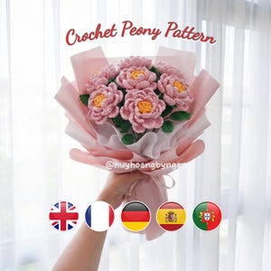 Puede incluir: Un ramo de peonías rosas de ganchillo con centros amarillos y hojas verdes, envuelto en papel rosa y blanco. El texto "Crochet Peony Pattern" se muestra encima del ramo. También es visible el identificador de Instagram @huyhoangbyngan.