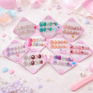 May include: A collection of press-on nails in various designs, including bows, stars, and cherries. Each set is displayed on a pink diamond-shaped card with the word "Dream" printed on it. The nails feature a range of colors and embellishments.