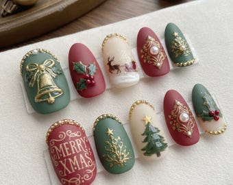 May include: A set of ten Christmas-themed false nails. Designs include a gold bell, holly, a reindeer-pulled sleigh, ornate gold patterns, a Christmas tree, and the text "MERRY XMAS" in red. The nails feature a matte finish with gold and pearl accents.