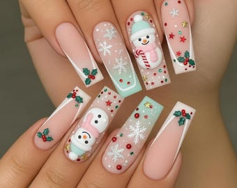 May include: A set of long, square-shaped acrylic nails with a festive winter theme. Each nail features a different design, including snowmen, snowflakes, holly, and star accents, in shades of pink, white, and mint green.