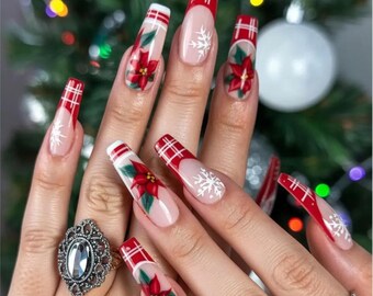 May include: Long, coffin-shaped acrylic nails with a Christmas theme. The nails feature a red plaid design, poinsettias, and white snowflakes. The nails are painted on a light pink base.