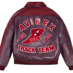 Może przedstawiać: Bordowa i fioletowa sk&oacute;rzana kurtka z białym napisem "AVIREX TRACK TEAM". Czerwono-biały emblemat USA jest wyśrodkowany na plecach. Kurtka ma prążkowany kołnierz i mankiety.