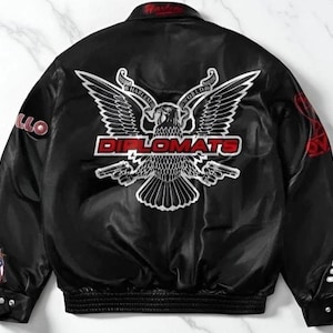 May include: Black satin bomber jacket with a large embroidered eagle design on the back, featuring the word "DIPLOMATS" in red. Additional patches and text are visible on the sleeves and collar. The jacket has a ribbed hem and cuffs.
