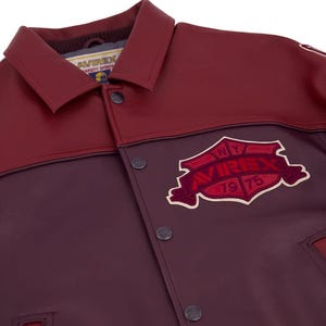 Może przedstawiać: Bordowa i kasztanowa kurtka w stylu college z zapięciem na guziki i kołnierzem. Kurtka posiada naszywkę z napisem "NY AVIREX 1975" w kształcie tarczy. Kurtka wykonana jest z materiału przypominającego sk&oacute;rę.