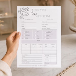 Puede incluir: Un formulario de pedido de pastel de panadería sostenido por una mano. El formulario incluye secciones para información del cliente, detalles del pedido y sabores de pastel. Un dibujo lineal de un pastel está en la parte superior. Un bloc de notas, un bolígrafo y un pastel están en el fondo.