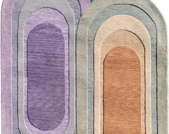 May include: Three oval-shaped rugs featuring concentric color bands. One rug displays shades of purple and lavender, another features blue and light blue tones, and the third showcases warm orange, beige, and sage green hues with a textured finish.