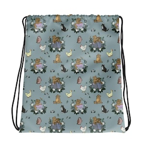 May include: A light blue drawstring bag featuring a repeating pattern of brown teddy bears, black and white cats, white chickens, yellow ducks, and brown owls, interspersed with small floral wreaths and green foliage elements throughout the design.