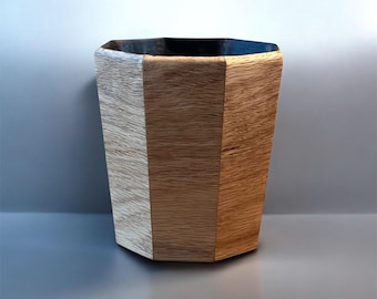 Puede incluir: Una taza geométrica de madera con un diseño multicolor. La taza presenta paneles alternos de madera clara y oscura, creando un contraste visual llamativo. El interior es de color oscuro y metálico.