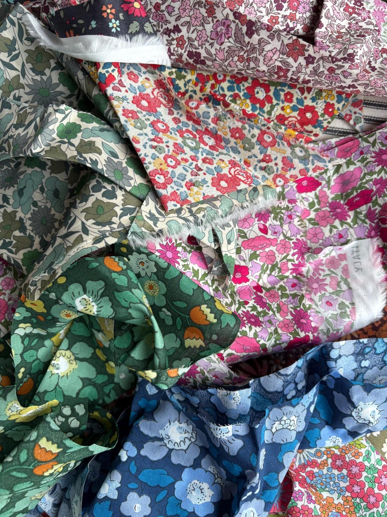 May include: A collection of floral fabric swatches in various colors. The fabrics feature a variety of flower patterns in shades of red, pink, blue, green, and purple. The image showcases the textures and colors of the fabric.