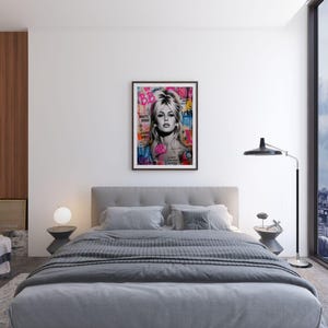 Puede incluir: Un cuadro enmarcado de arte pop con un retrato de una mujer rubia con las letras "BB" en la esquina superior izquierda. La obra de arte se exhibe sobre una cama gris con almohadas a juego y una manta gris oscura. La habitaci&oacute;n tiene un dise&ntilde;o moderno.