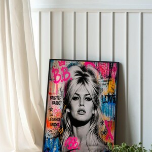 Puede incluir: Retrato en blanco y negro de Brigitte Bardot con arte de graffiti colorido. La obra de arte incluye el texto "B.B", "Brigitte Bardot" y "La L&eacute;gende Bardot". La pieza est&aacute; enmarcada en un borde negro.