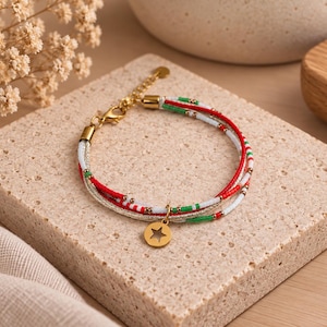 Peut inclure: Un bracelet multi-brins composé de fines cordes ornées de perles de rocaille rouges, blanches et vertes, agrémenté d'entretoises dorées et d'une breloque étoile dorée. Le bracelet possède un fermoir mousqueton doré et une chaînette réglable.