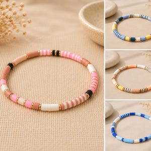 Könnte beinhalten: Eine Sammlung von vier kreisförmigen Armbändern aus kleinen, flachen, scheibenförmigen Perlen in verschiedenen Farbpaletten wie Rosa, Blau, Weiß, Gelb und Braun, akzentuiert mit kleinen, runden, metallisch goldfarbenen Zwischenperlen.