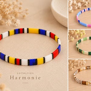Pode incluir: Uma coleção de quatro pulseiras finas feitas de pequenas contas planas retangulares em vários padrões de cores. A pulseira principal apresenta segmentos amarelos, vermelhos, azuis, pretos e brancos. O texto 'collection Harmonie' está impresso abaixo.