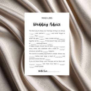 May include: A white Mad Libs game sheet titled "Wedding Advice" with fill-in-the-blank prompts. The sheet includes instructions for a happy marriage, with spaces for nouns, verbs, and adjectives. The text is in black, with a cursive "Wedding Advice" title.