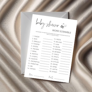 May include: A white baby shower word scramble game card with a matching envelope. The card features the words "baby shower" in cursive, a word scramble, and lines for names and points. The background is a neutral color.