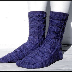 Op de afbeelding: Een paar paarse gebreide sokken met een kabelbreipatroon.