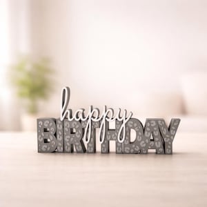 Könnte beinhalten: Ein dekoratives Schild mit der Aufschrift "happy birthday". Das Wort "happy" ist in weißer Schreibschrift geschrieben, und "birthday" in grauen Blockbuchstaben mit einem Leopardenmuster. Eine stilvolle Geburtstagsdekoration.